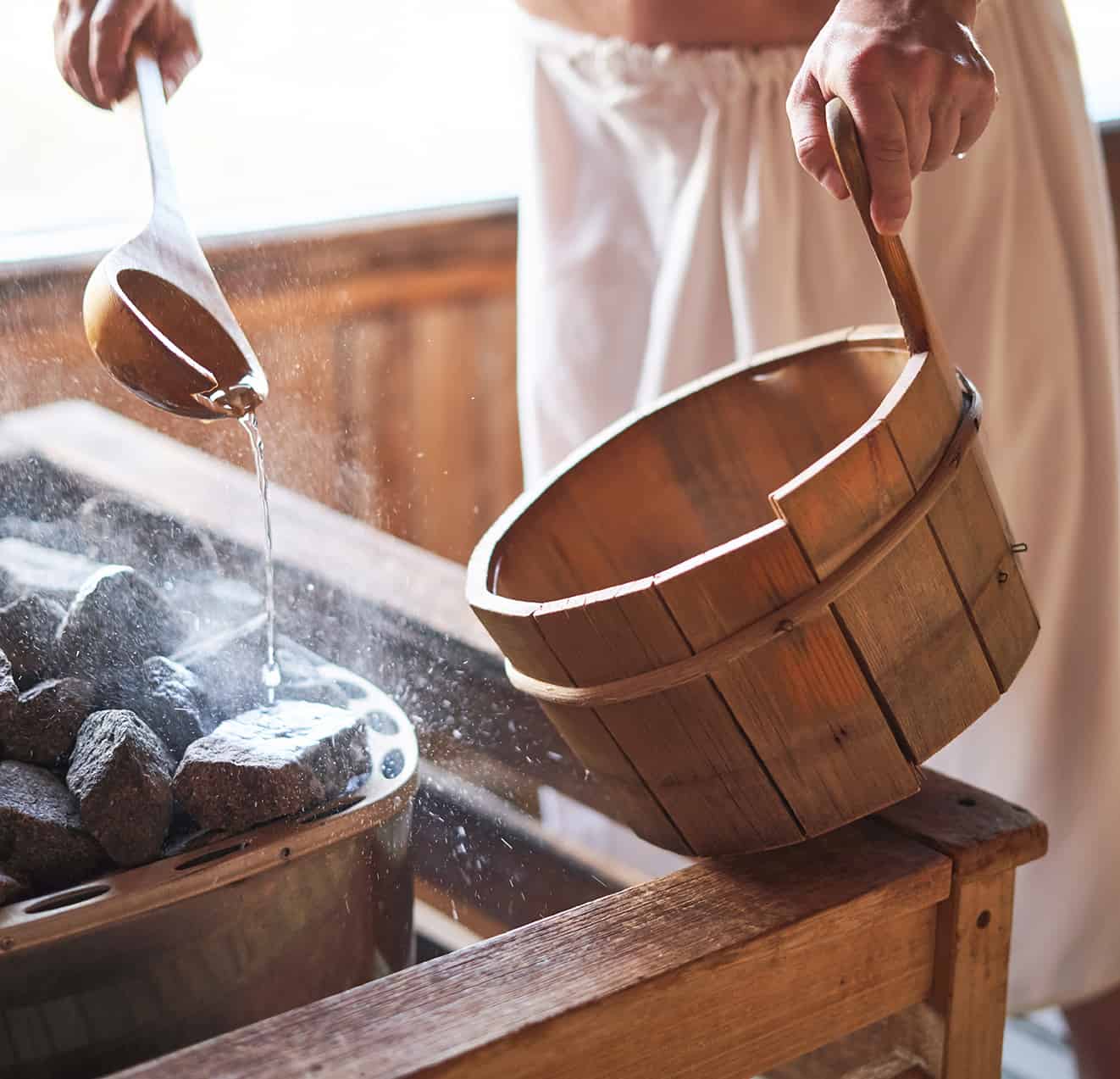 Mann gießt Wasser auf heiße Steine in der finnischen Sauna der Therme Loipersdorf